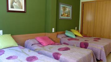 Une chambre avec deux lits, des murs verts et une porte en bois.