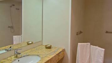 Un baño moderno con lavamanos de granito, un espejo grande y una ducha a ras de suelo.
