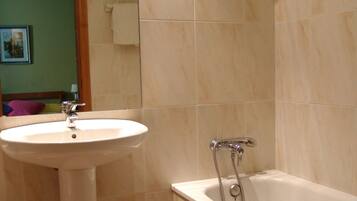 Un baño con lavamanos, espejo y bañera.