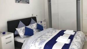 Un dormitorio ordenado con cama, mesitas de noche, armario y un cuadro en la pared.