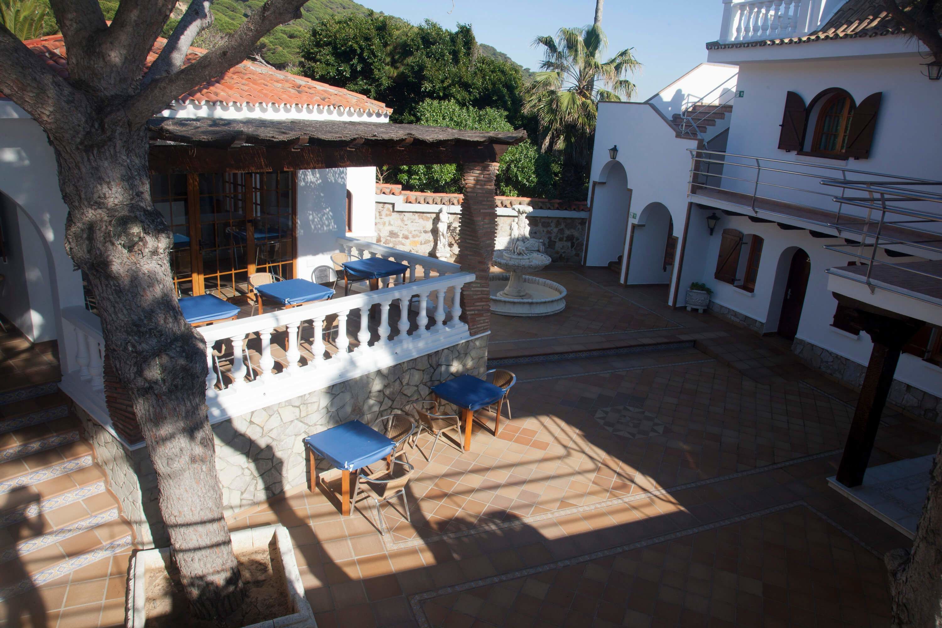 A courtyard with a covered seating area, stone walls, and a fountain.