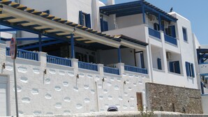 A white building with blue accents, balconies, and a stone wall. - Blue Waves View (Andros)