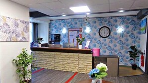 Un área de recepción con mostrador de piedra, un reloj y papel tapiz estampado.
