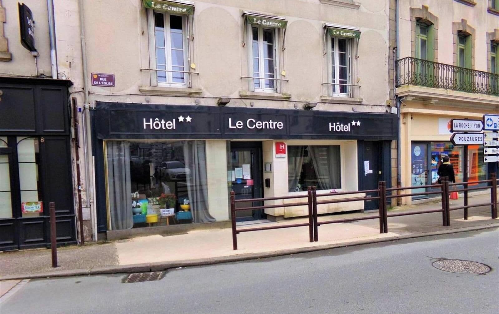 Un edificio con dos letreros de hotel, una entrada principal y una acera.