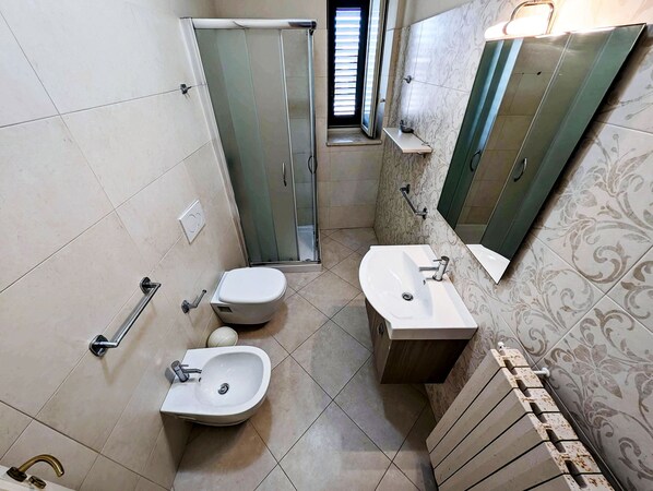 A bathroom with a toilet, bidet, sink, and shower. - Oikia Vacanze Diso Chiara (Diso)