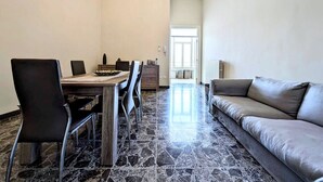 Ein Essbereich mit Holztisch und Stühlen, einer Chandelüster und einer Couch in einem modernen Ambiente.