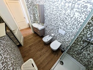 A bathroom with a tiled mosaic backsplash, a wooden floor, a white sink, a bidet, and a toilet. - Oikia Vacanze Diso Chiara (Diso)