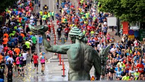 A bronze statue of a figure with a water spout, surrounded by a crowd of runners. - Eklanda Heden (Gothenburg)