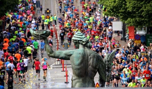 A bronze statue of a figure with a water spout, surrounded by a crowd of runners. - Eklanda Heden (Gothenburg)