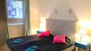 A bedroom with a bed, two bedside lamps, and a window with blinds. - Eklanda Heden (Gothenburg)
