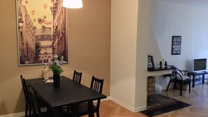 A dining area with a black table and chairs, a vase with flowers, a hanging light fixture, and a large framed picture on the wall. - Eklanda Heden (Gothenburg)