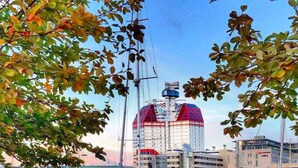 A waterfront scene with a bench, boats, and a building with a distinctive red and blue dome. - Eklanda Heden (Gothenburg)