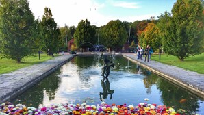 A serene garden with a fountain, a pathway, and a variety of colorful flowers. - Eklanda Apartment Lilla Bommen (Gothenburg)