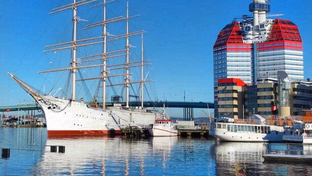 A tall ship docked at a harbor with a modern building in the background. - Eklanda Apartment Lilla Bommen (Gothenburg)