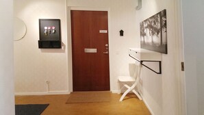 A hallway with a wooden door, a coat rack with keys, a small shelf, and a framed picture on the wall. - Eklanda Apartment Lilla Bommen (Gothenburg)