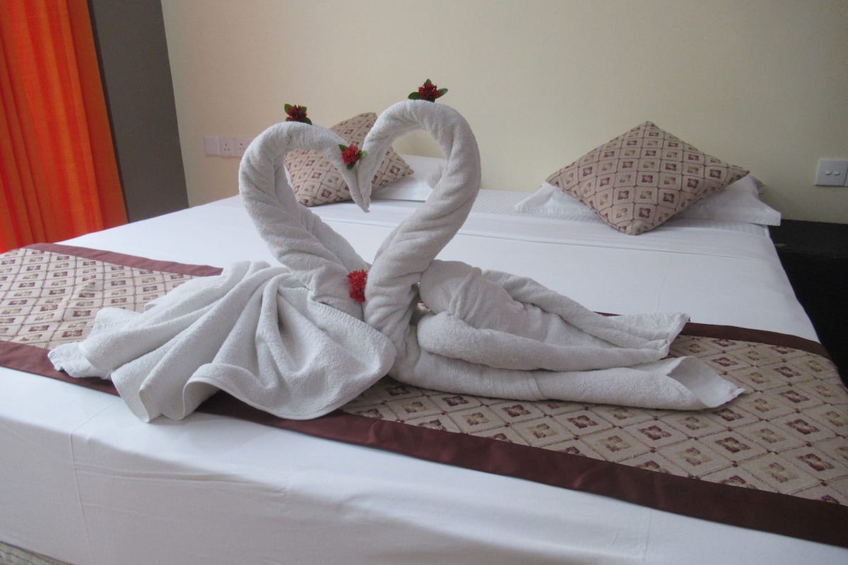 A hotel room with a bed featuring a decorative towel swan centerpiece.