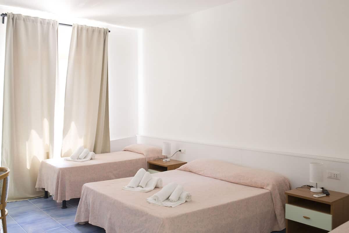 Habitación de hotel con dos camas, cada una con una mesita de noche, una lámpara y un teléfono.