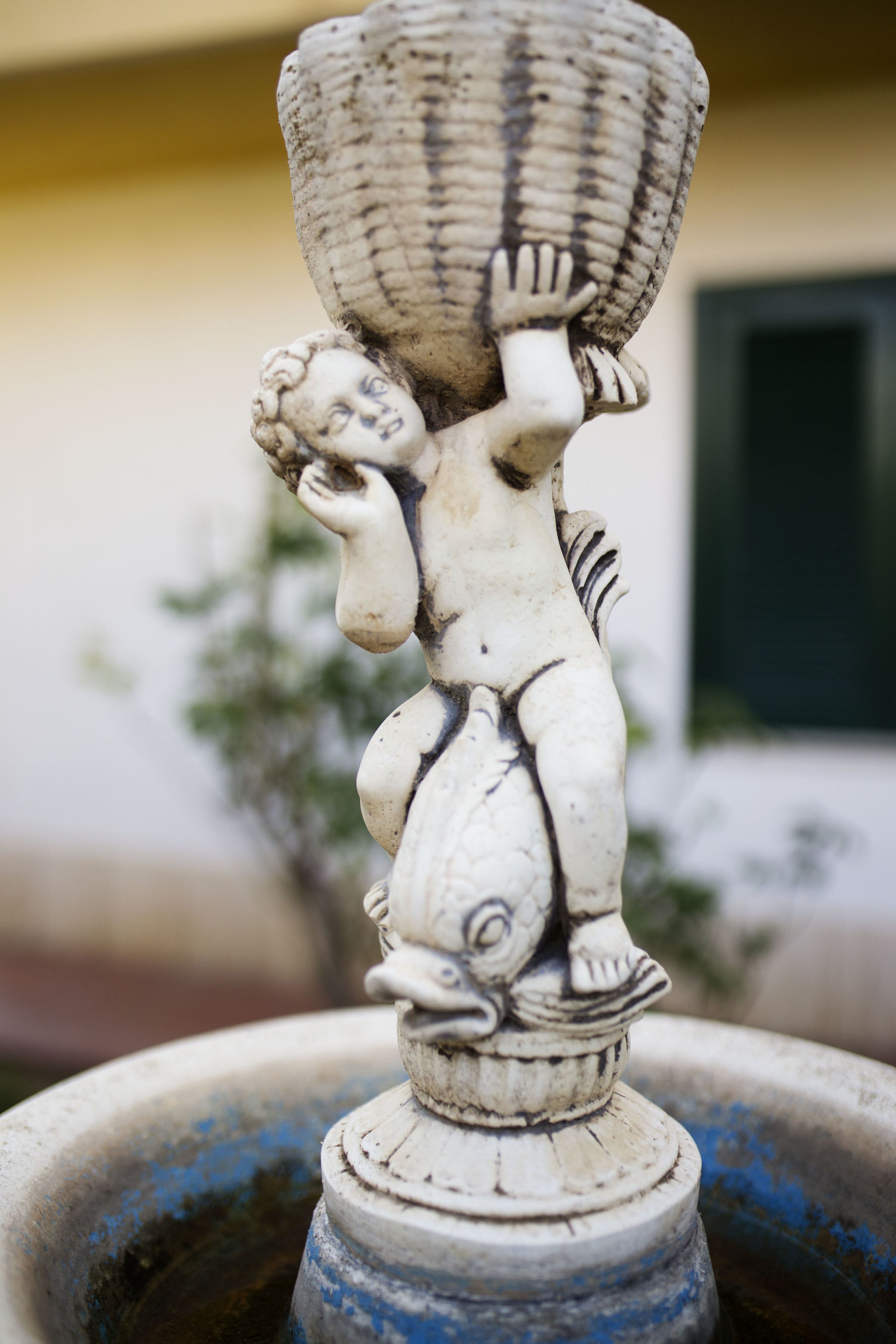 Une statue en marbre blanc représentant une figure tenant un panier, placée sur un piédestal.