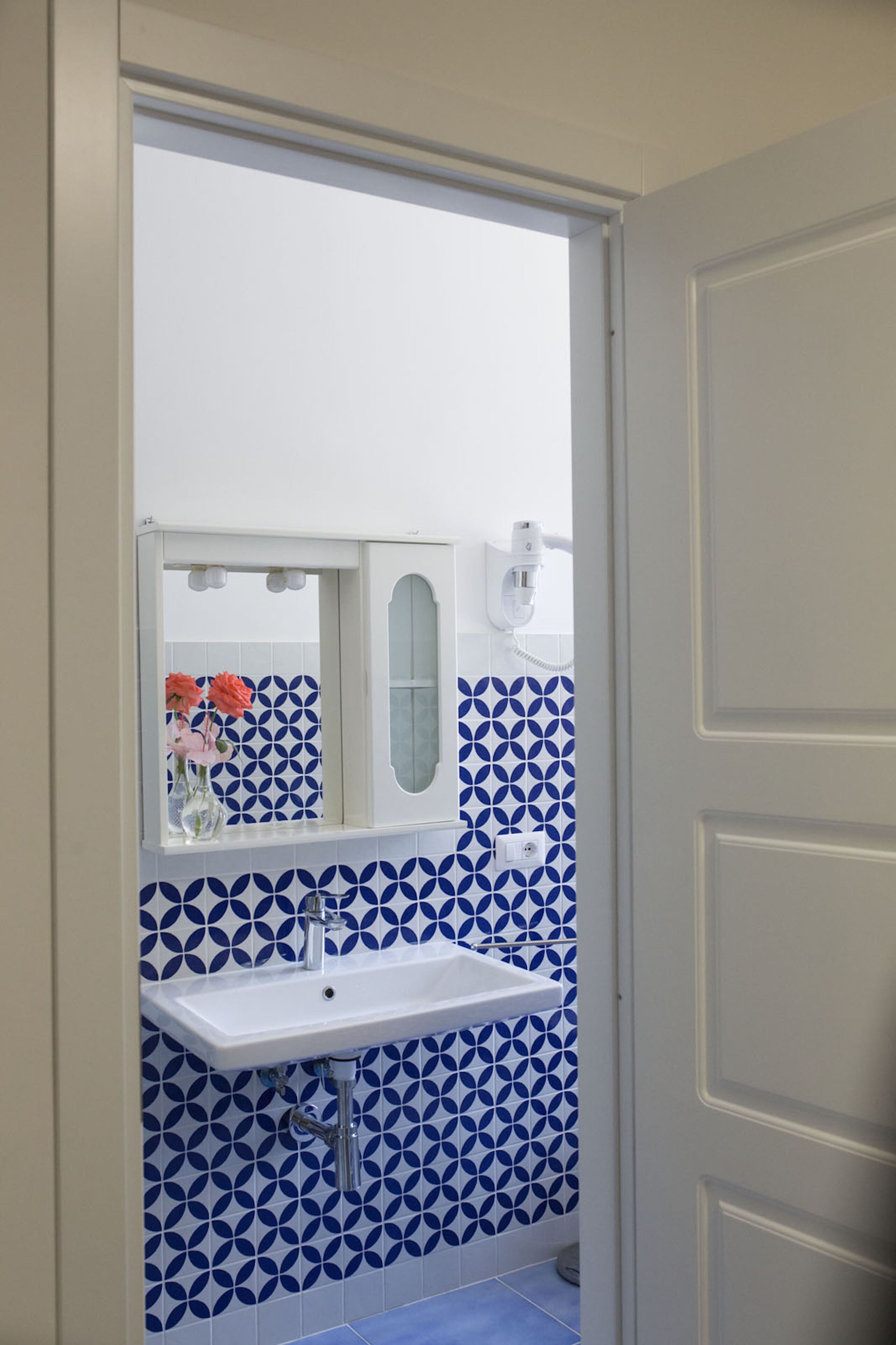 A bathroom with a white sink, blue patterned tiles, and a mirror.
