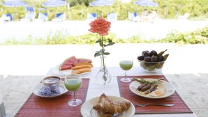 A table with a croissant, a plate with sausages and eggs, a bowl of grapes, a glass of green juice, and a watermelon slice. - B&B Il Cavaliere (Ricadi)