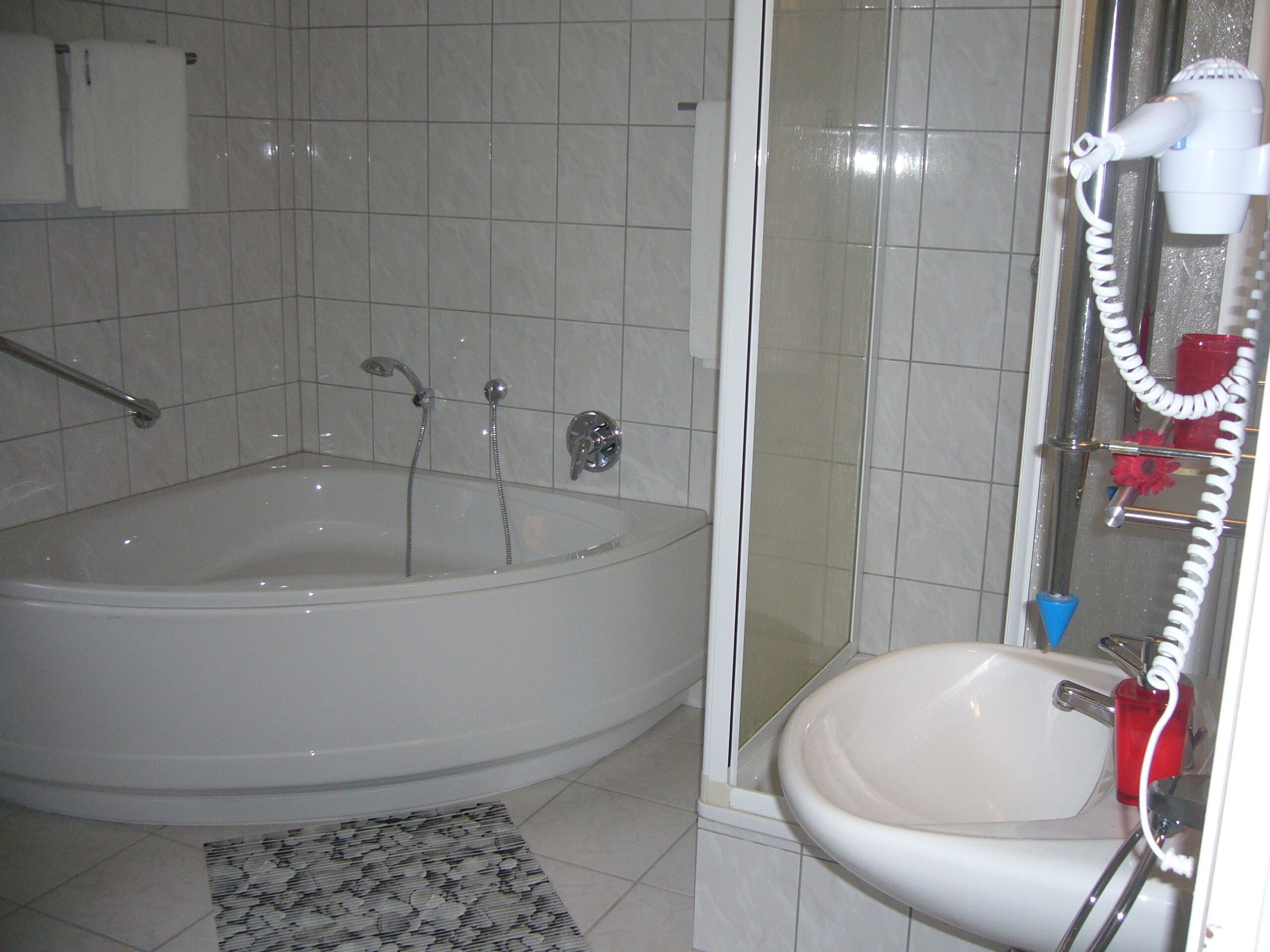Un baño con bañera, ducha y lavamanos.