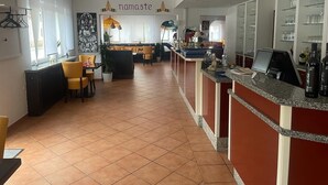 Un moderno vestíbulo de hotel con mostrador de recepción, zona de estar y una gran obra de arte en la pared.