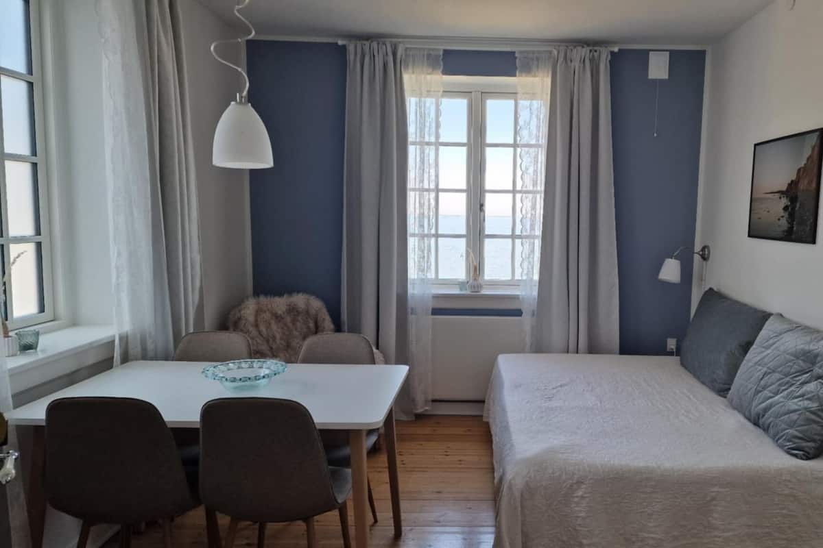 Una habitación pequeña con una cama, una mesa de comedor y sillas.