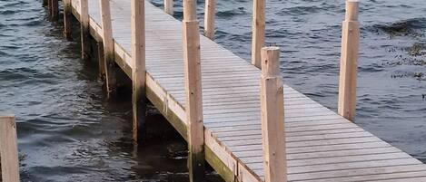 Un muelle de madera que se extiende sobre aguas tranquilas, con un cielo despejado al fondo.
