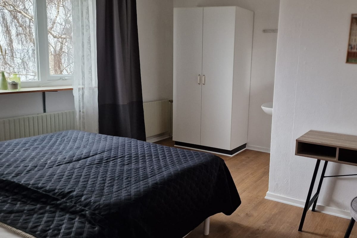 Un dormitorio con cama, armario, escritorio y silla.