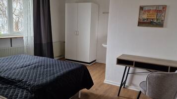 Een slaapkamer met een bed, een kledingkast, een bureau en een stoel.