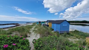 A row of colorful beach huts along a sandy path by the water. - Hotel Udsigten Marstal (Marstal)