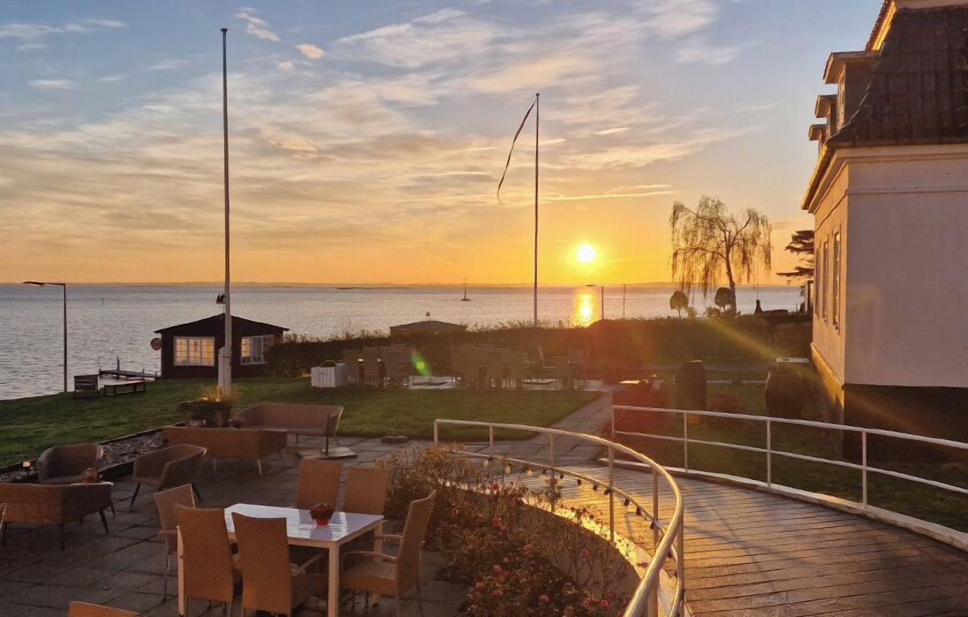A sunset view from a terrace with outdoor seating and a view of the sea.