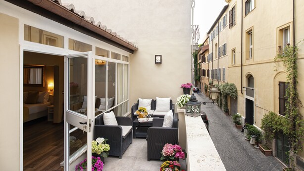 A narrow courtyard with outdoor seating, a bed, and a view of adjacent buildings. - Canova Rooms in Spanish Steps (Rome)
