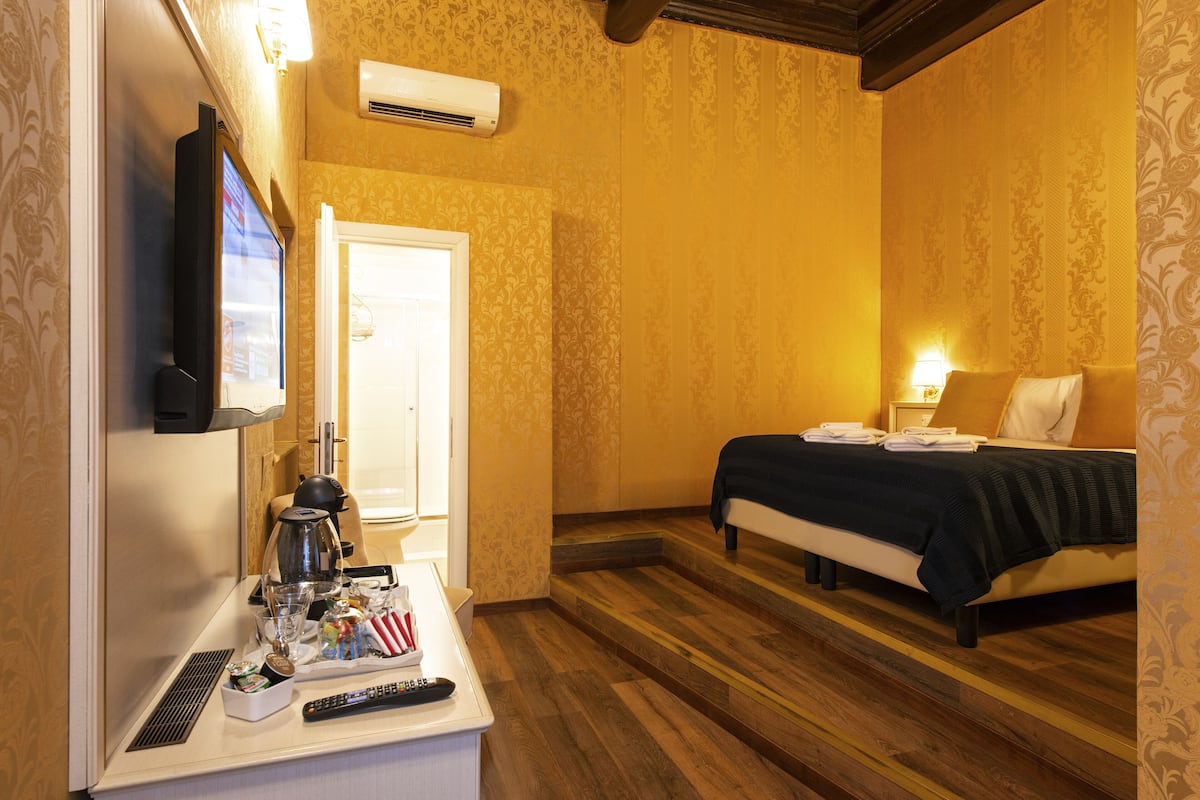 A hotel room with a bed, bedside table, and a television.