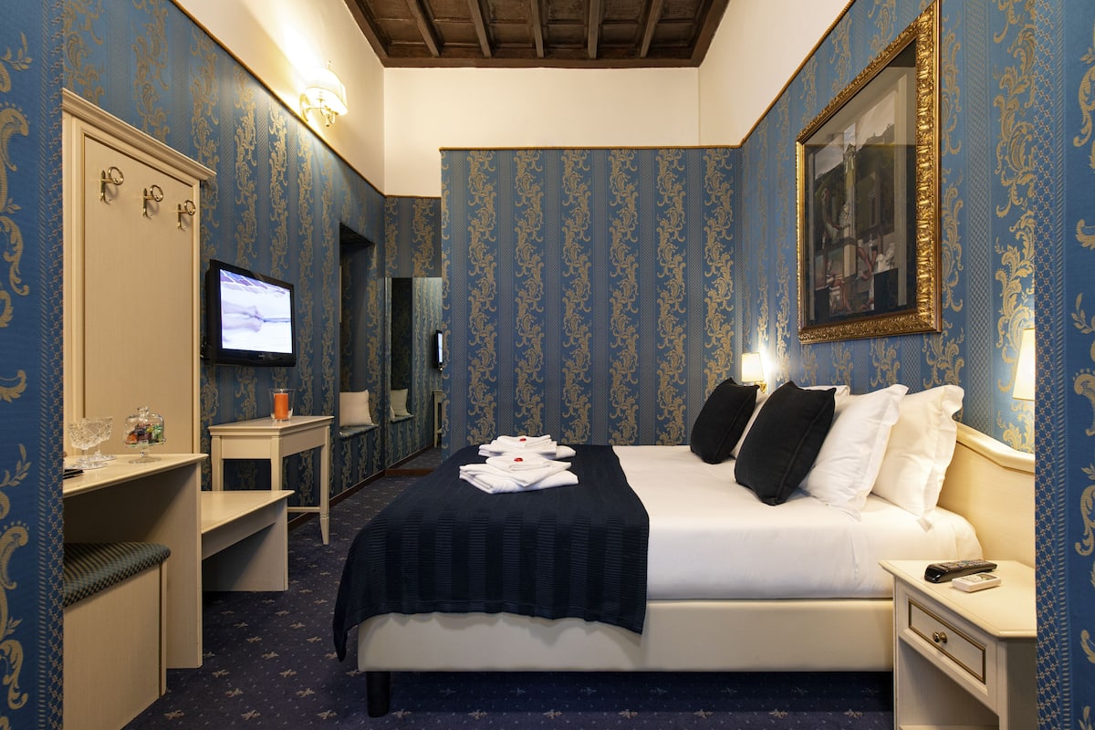 A hotel room with a bed, a desk, a television, and a mirror.