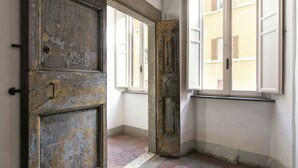 An interior corridor with a weathered door and windows. - Canova Rooms in Spanish Steps (Rome)