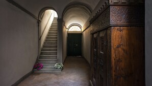 A hallway with a staircase, a wooden cabinet, and a door at the end. - Canova Rooms in Spanish Steps (Rome)