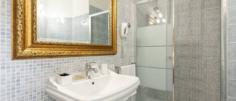 A bathroom with a white sink, a gold-framed mirror, and a glass-enclosed shower.