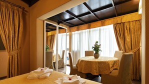 A hotel room with a bed, a dining table with chairs, and a potted plant. - Canova Rooms in Spanish Steps (Rome)