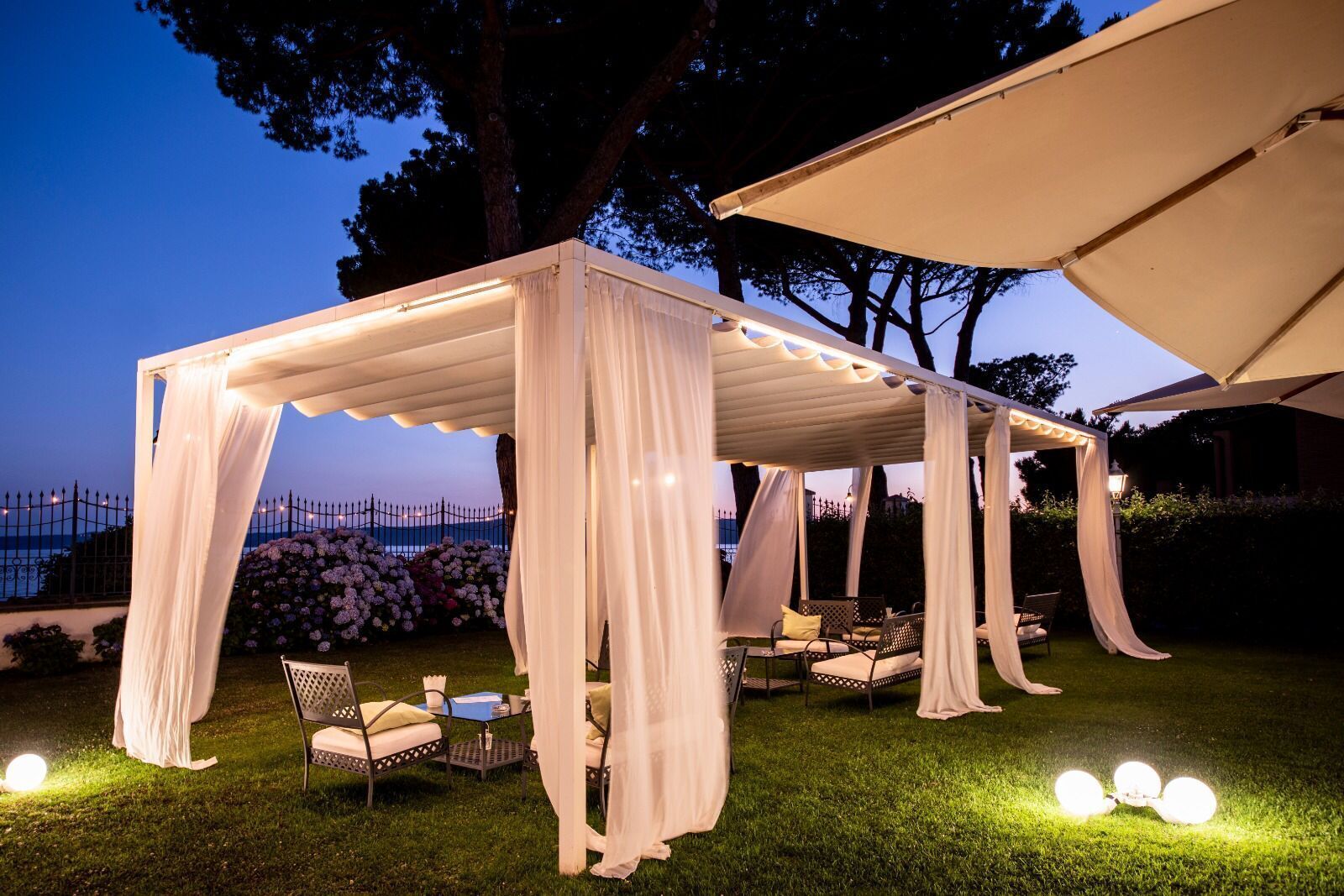 An outdoor tented area with white drapery and seating arrangements.