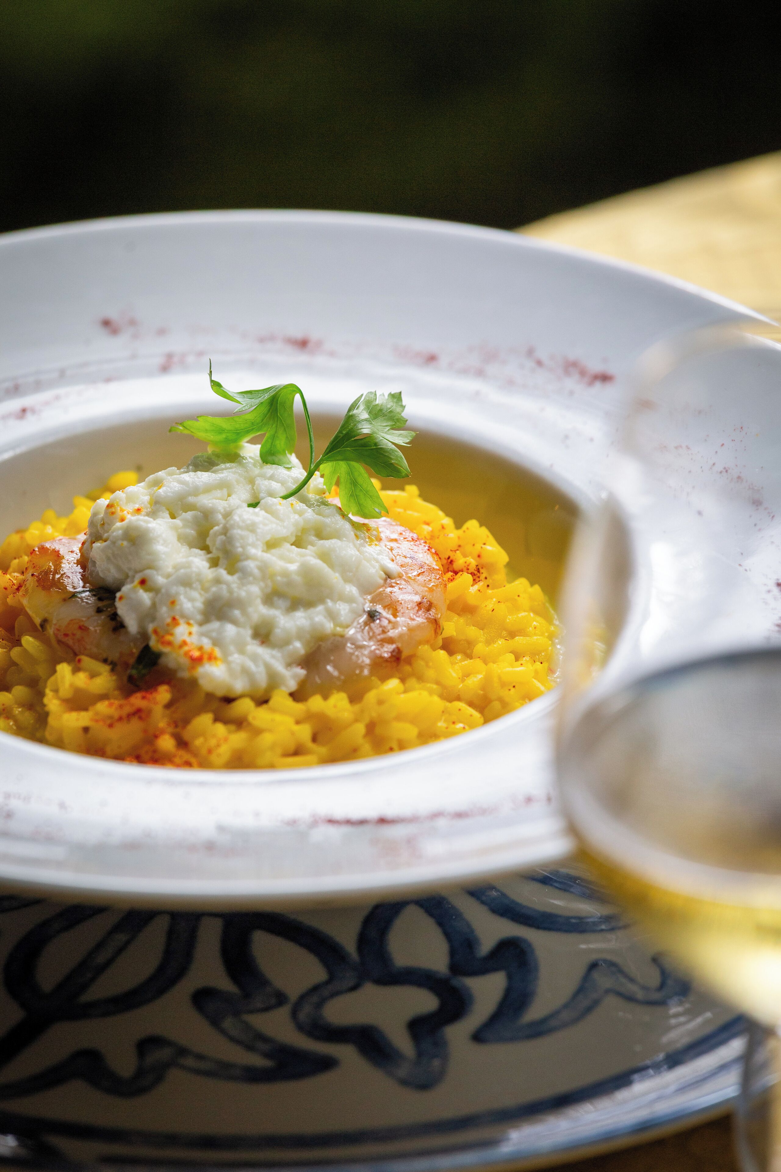 Un tazón de arroz amarillo con una cucharada de salsa blanca y decoración, servido en un plato estampado.