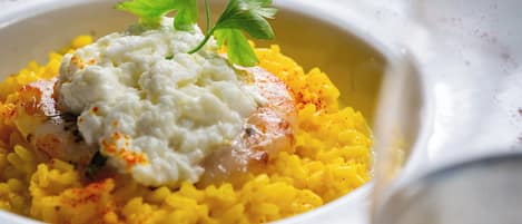 Un tazón de arroz amarillo con una cucharada de salsa blanca y decoración, servido en un plato estampado.