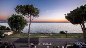 A coastal view with a clear sky, a calm sea, and a road with a sidewalk and benches. - Hotel Holiday (Bolsena)
