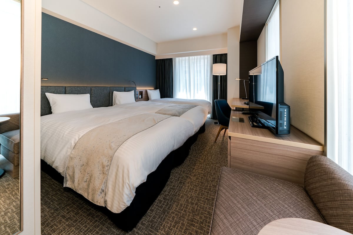 A hotel room with a large bed, a desk with a computer, a television, and a view of the outdoors.