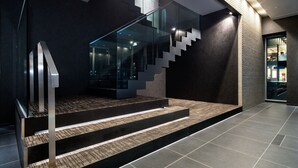 Una escalera moderna con barandillas de vidrio y una baranda metálica, que conduce a un segundo piso.