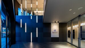 Un moderno vestíbulo de hotel con un muro de cristal, una escalera y un cartel de Daewoo Ryonet Hotel.