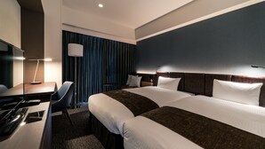 Habitación de hotel con una cama grande, un escritorio con computadora, una silla y una lámpara.