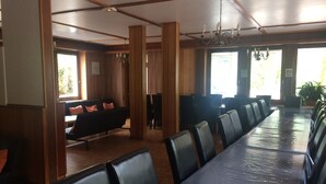 A conference room with a long table and chairs, wooden paneling, and a chandelier. - Les Sources (Bussang)