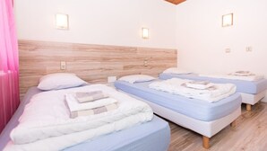 A hotel room with three beds, wooden headboard, and wall-mounted lights. - Les Sources (Bussang)