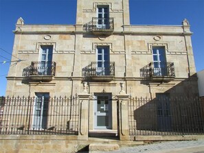 A stone building with three balconies, a central entrance, and a wrought iron fence. - Posada Real El Brasilero (Saucelle)